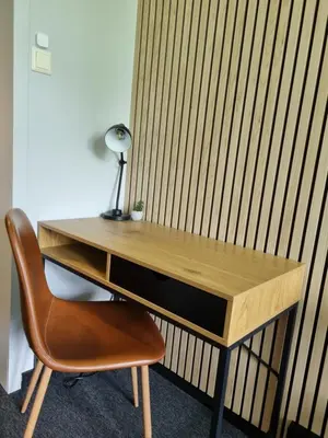 a wooden desk with a lamp and a chair at A11 Apartments in Ålesund