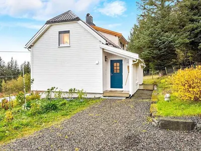 a small white house with a blue door at 6 person holiday home in MIDSUND-By Traum in Aukra