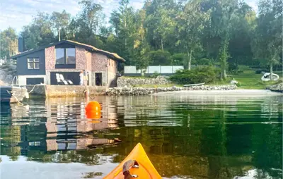 a house in the water with a kayak in front of it at 3 Bedroom Amazing Home In Skjold in Skjold
