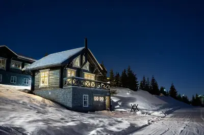 a large house in the snow at night at Hafjell tømmerhytte 4B in Hafjell