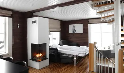 a living room with a fireplace and a bed at Hafjell tømmerhytte 4B in Hafjell