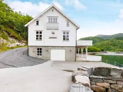 a white house with a driveway next to a body of water at 8 person holiday home in Ørskog-By Traum in Ørskog