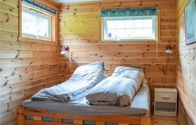 a bed in a room with a wooden wall at 6 Bedroom Beautiful Home In Vossestrand in Vossestrand