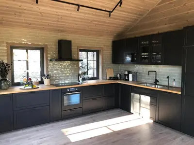 a kitchen with black cabinets and wooden ceilings at Høgerinden Lodge in Sogndal