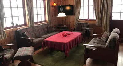 a living room with a table and a couch and chairs at Berghstua - Natrudstilen på Sjusjøen in Sjusjøen