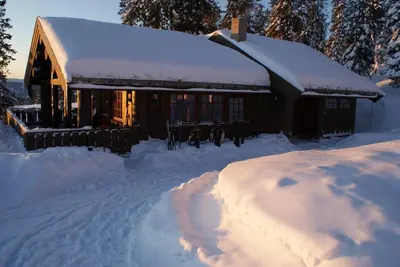 a cabin covered in snow with a pile of snow at Berghstua - Natrudstilen på Sjusjøen in Sjusjøen