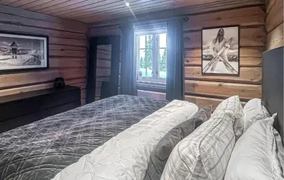 a bedroom with a bed in a room with wooden walls at Cozy Home In Sjusjøen With Sauna in Sjusjøen