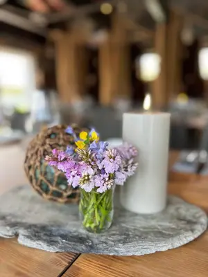 a vase of flowers on a table next to a candle at Torvholmen in Fosnavåg
