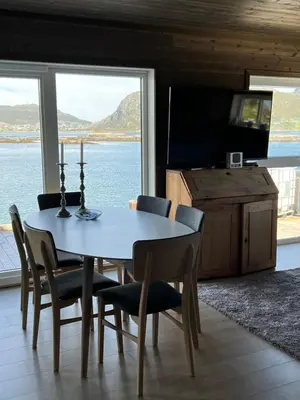 a dining room with a table and chairs and a television at Torvholmen in Fosnavåg