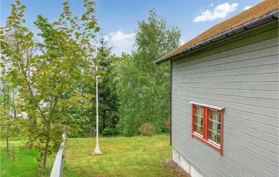 a gray house with a window and a tree at 3 Bedroom Awesome Home In Leikanger in Leikanger