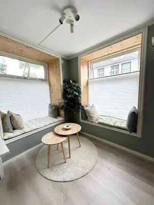 a living room with two windows and a table at Apartment «Ladegården» in Bergen in Bergen