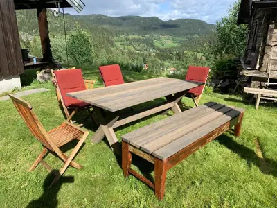a wooden table and chairs and a wooden bench at Kultan in Åmotsdal
