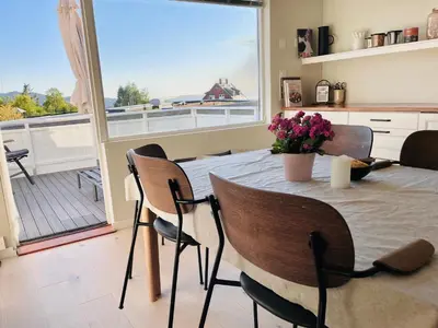 a dining room with a table and chairs and a balcony at Floien City House -free parking in Bergen