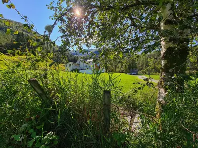 a field of grass with a house in the background at Jondal Nice apartment with bed linen incuded in Jondal