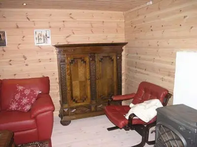 a living room with two red chairs and a wooden wall at Jondal Nice apartment with bed linen incuded in Jondal