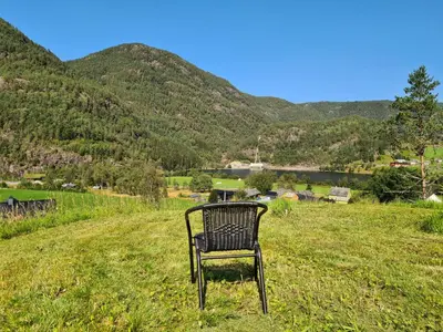 a chair sitting in a field with mountains in the background at Jondal Nice apartment with bed linen incuded in Jondal