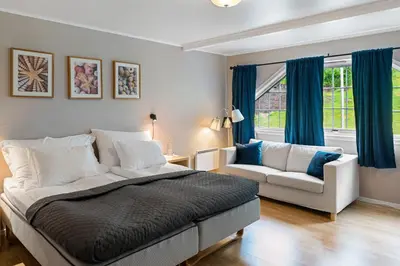 a bedroom with a bed and a couch and a window at Moens Motell in Fiskå