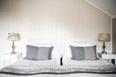 a bedroom with two white beds and two lamps at Moens Motell in Fiskå