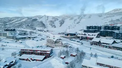 a town covered in snow with mountains in the background at Gjestegaarden Leiligheter in Beitostøl