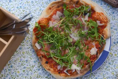 a pizza with greens on a plate on a table at Kyrkjestølen B&B in Tyinkrysset