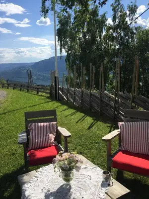 two chairs and a table in the grass with a view at Glomstad Gjestehus in Tretten