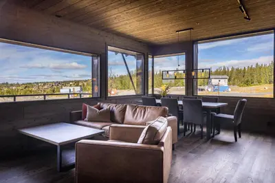 a living room with a couch and tables and windows at Mosetertoppen Skiline - Hafjell Ski Resort in Øyer