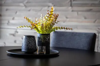 a black table with a vase of flowers and a candle at Mosetertoppen Skiline - Hafjell Ski Resort in Øyer