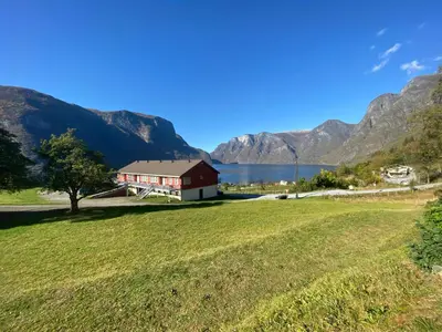 a red barn in a field with mountains in the background at Winjum Hostel Stegastein in Aurland