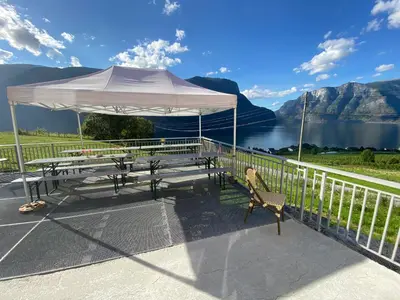 a picnic table with a white umbrella and a lake at Winjum Hostel Stegastein in Aurland