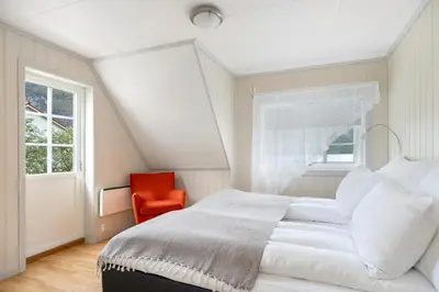 a bedroom with a white bed and a red chair at Aurland Guesthouse in Aurland