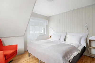 a bedroom with a large bed and a red chair at Aurland Guesthouse in Aurland