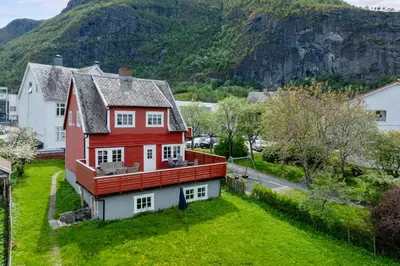 a red house on a green field with a mountain at Aurland Guesthouse in Aurland