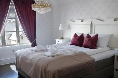 a bedroom with a large white bed with purple pillows at Sylte Hotell, Valldal in Valldal