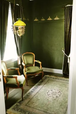 a green room with two chairs and a chandelier at Sylte Hotell, Valldal in Valldal