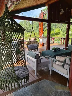 a porch with chairs and a swing and a table at DaVita Ranch in Tranhaug