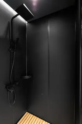 a bathroom with a shower with a black wall at Sogndal Fjordpanorama - Studio Cabins With View in Sogndal