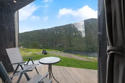 a porch with chairs and a table and a view of a mountain at Sogndal Fjordpanorama - Studio Cabins With View in Sogndal