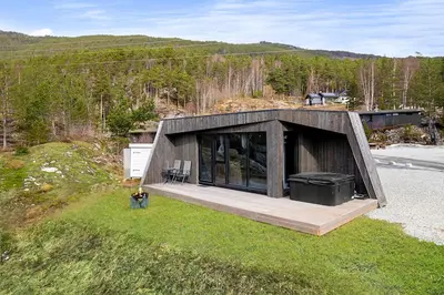 a person standing in front of a house at Sogndal Fjordpanorama - Studio Cabins With View in Sogndal
