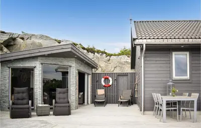 a house with a patio with a table and chairs at Nice Home In Sveio With House Sea View in Sveio