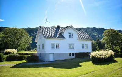 a white house with a roof on a grass field at Awesome Home In Fitjar With Wifi in Fitjar