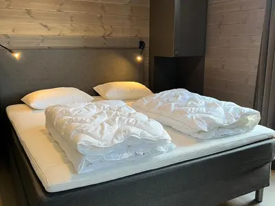 two unmade beds with white blankets and pillows at Riddertunets moderne in Beitostøl