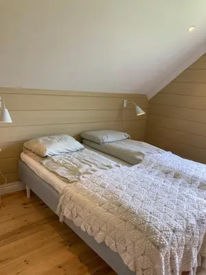 two twin beds in a room with wood floors at Nesje Gardstun in Oppstryn