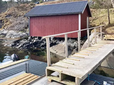 a dock with a red building with stairs in the water at 6 person holiday home in Halsanaustan-By Traum in Korsnes