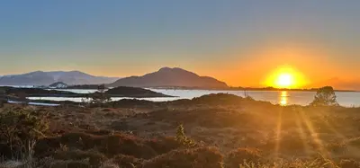 a sunset over the water with mountains in the background at Ytterland Apartments in Ålesund