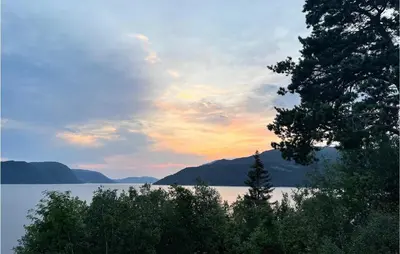 a sunset over a lake with trees in the foreground at 4 Bedroom Nice Home In Stangvik in Stangvik