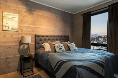 a bedroom with wooden walls and a bed with a window at Riddertunets luksuriøse in Beitostøl