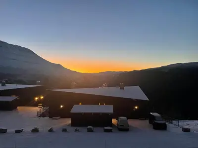 a sunset over a barn with snow on the ground at New apartment, Gausta in Rjukan. Ski in/ ski out in Rjukan