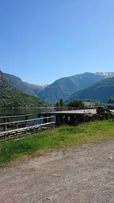 a dock on a lake with mountains in the background at Hillegård in Lærdalsøyri