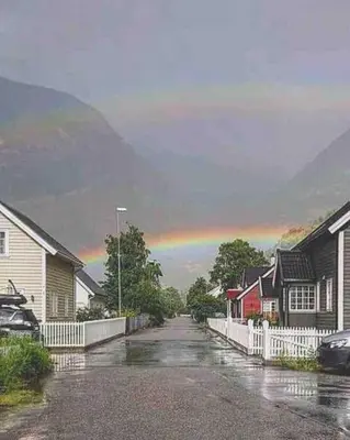 a rainbow in the sky over a street with houses at Hillegård in Lærdalsøyri