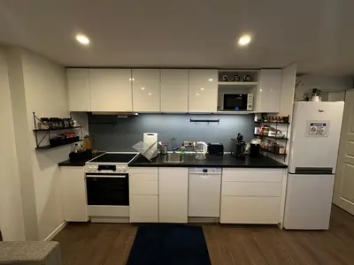 a kitchen with white cabinets and a white refrigerator at Great place with a stunning view of the mountains and the fjord in Ålesund